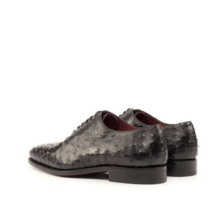 Black ostrich leather whole-cut oxford shoes with a smooth leather sole and dark red lining.