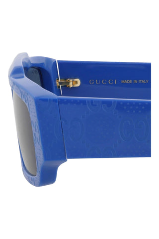 Shiny brilliant blue Gucci square sunglasses featuring embossed Guccissima logo pattern on recycled acetate frames.